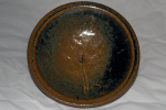 Stoneware dish that is tan on the edges and in the center where a tomato leaf imprint is, but blueish in between due to reduction in the firing.